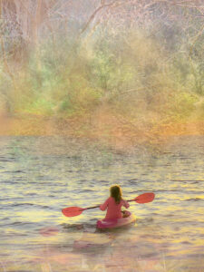 girl paddling in water with trees in background