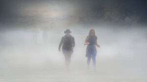 two people walking out of a misty environment